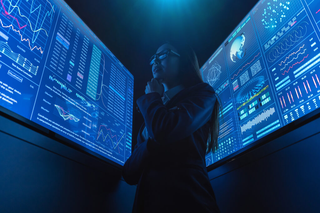 Executive analyzing real-time cybersecurity and operational data across multiple digital dashboards during a cyber incident response scenario.