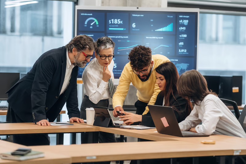 Executive leadership team reviewing business analytics dashboards and collaborating on AI strategy, operational performance, and data-driven decision-making.