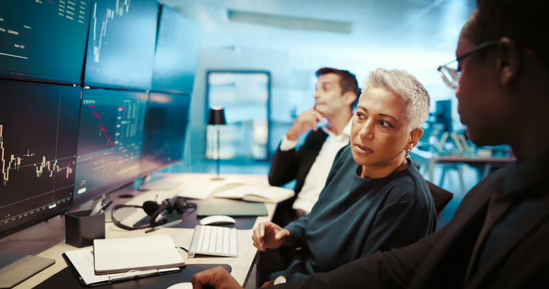 Business leaders reviewing technology risk data and digital infrastructure performance on multiple screens.